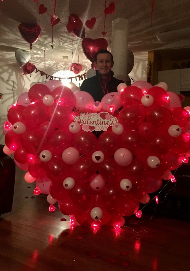 Large heart-shaped balloon wall in red and pink with lights, built for a Valentine's celebration