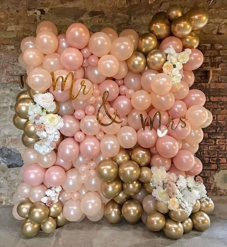 Wedding balloon wall spelling Mr & Mrs in blush, rose gold and chrome gold with flowers, built against exposed brick